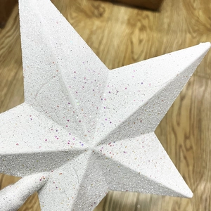 Close-up of a white pentagram Christmas tree topper covered in sparkling colorful glitter