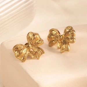 Chic golden bow-knot stainless steel stud earrings displayed on minimalist beige background