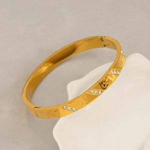 Detailed macro view of gold-plated titanium clover bracelet featuring white rhinestones