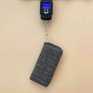 Gray striped long wallet for women being weighed on a digital scale showing 0.115kg