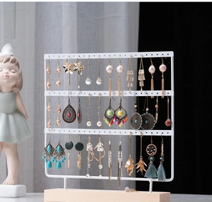 Three-tier white iron earring display stand with wooden base and various jewelry items