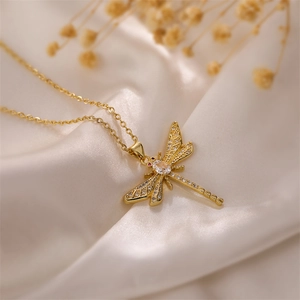 Macro shot of gold dragonfly necklace with white rhinestones on silk fabric