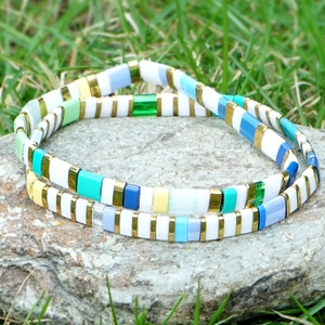 Handmade Tila bead bracelets in vibrant colors on a natural rock with a summer beach style
