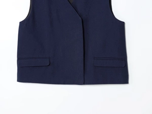 Detailed close-up of dark blue vest waist featuring symmetrical flap pockets and twill fabric