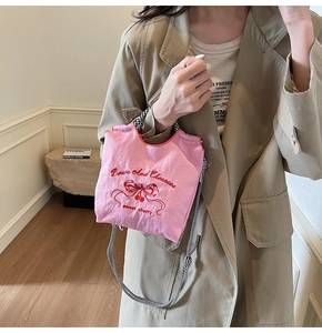 Pink nylon handbag with cherry embroidery and checkered handle shown on a model