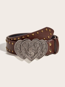 Detail of brown leather belt featuring brass studs and a vintage carved heart buckle