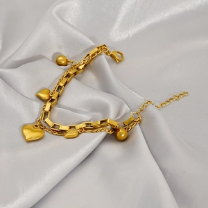 Détail du bracelet double couche avec cœurs dorés sur fond de satin argenté doux