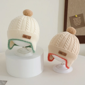 Knitted baby winter earflap hat with pom-pom and cozy twist pattern in earth tones