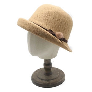 Detailed texture of beige knit bucket hat featuring a brown ribbon and plush pom-pom decor