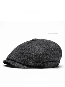 Detail of dark grey newsboy cap showing thick wool texture and top button detail