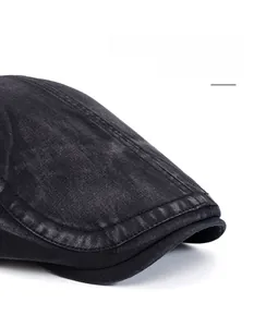 Detail of washed black cotton flat cap featuring reinforced stitching and wide brim