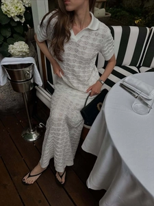 Detail of white knit polo top and cutout maxi skirt in a luxury outdoor restaurant setting