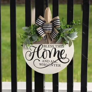 Detail of wooden welcome sign with burlap bow, green plants, and home blessing text
