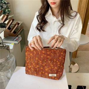 Trousse à maquillage vintage en velours côtelé fleuri rouge rouille tenue à la main