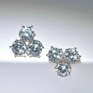 Macro-opname van zilveren cluster oorbellen met drie zirkonen en klauwzetting