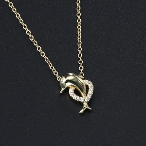 Close-up of golden dolphin necklace with sparkling zircon heart-shaped pendant details