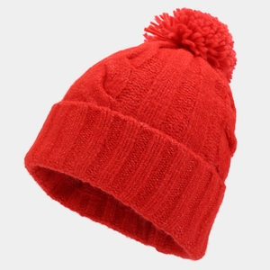 Detail of red cable knit winter beanie with soft faux fur pom-pom and folded cuff edge