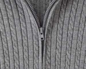 Detailed macro view of the grey cable knit sweater texture and sturdy metal zipper closure