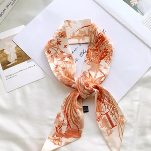 Detailed view of cream and orange silk twilly scarf with elegant hand-painted bird motifs