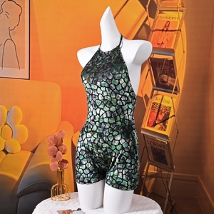 Halter neck jumpsuit with green and black stone pattern in a stylish home setting