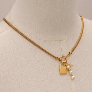 Gold snake chain necklace with pearl accents and letter A padlock pendant on mannequin