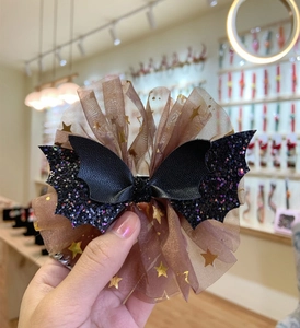 Close-up of Halloween bat hair clip with glitter wings and golden star mesh
