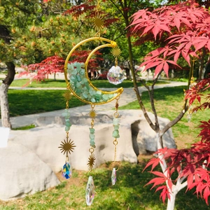 Detail of moon suncatcher with green natural crushed stones and golden star pendants