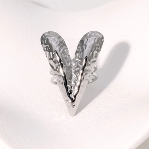 Silver elongated heart ring with hammered metal texture on white wavy background