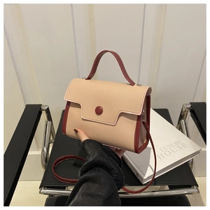 Detail of beige and burgundy pebbled leather handbag with handle and detachable strap