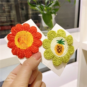 Close-up of handmade crochet flower hair clips featuring strawberry and pineapple designs