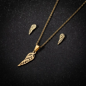 Détail du collier aile d'ange doré et des boucles d'oreilles assorties sur fond noir scintillant