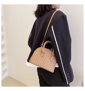 Model showing beige quilted shell bag in a minimalist indoor setting with natural light