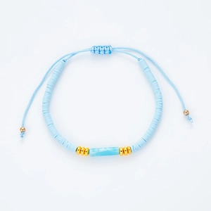 Detail eines verstellbaren blauen Perlenarmbands mit Edelstein und Goldakzenten