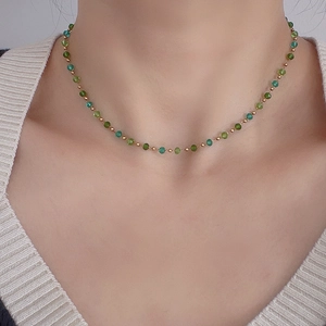 Close-up of green gradient crystal beads and 18k gold steel balls on a choker necklace