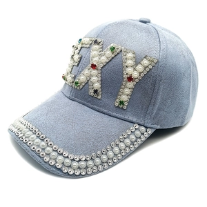 Détails macro des ornements 'SEXY' en strass et perles sur casquette de baseball en daim bleu