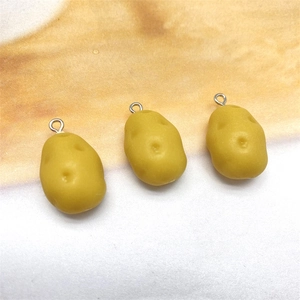 Macro shot of realistic yellow resin potato charms with silver metal rings for DIY
