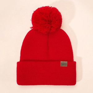 Red knit pom-pom beanie for kids with a ribbed texture and fashion logo patch