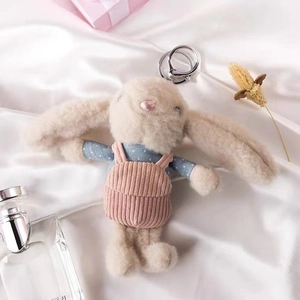Detail of cute long-eared plush rabbit keychain with pink corduroy overalls and blue shirt