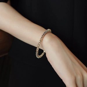 Detailed view of a gold geometric bracelet with a textured crushed gold finish on a wrist