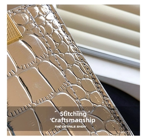 Macro view of gold crocodile embossed leather handbag with precise stitching details