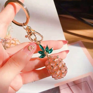 Close-up of pink opal pineapple keychain with gold lobster clasp and green rhinestone leaves