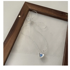 Detail of S925 silver heart necklace with blue zircon on a minimalist wood frame