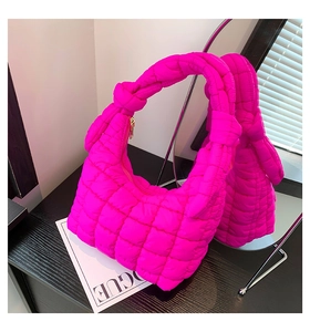 Detail of hot pink quilted cloud bag featuring knotted handle and gold metal zipper