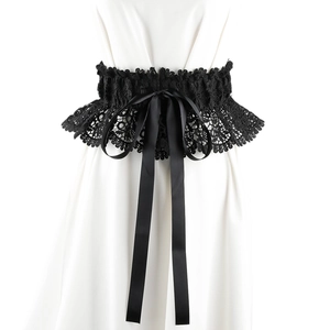 Detailed texture of black lace waist belt featuring a satin ribbon bow on white clothing