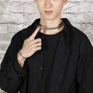 Silver Cuban chain necklace and bracelet set shown on model against a gray wall background