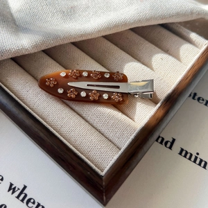 Gros plan d'une barrette à cheveux écaille de tortue avec motifs floraux en strass