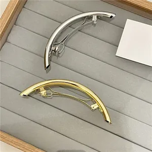 Close-up of polished gold and silver metal arch hair clips on a velvet tray