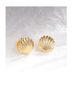 Detailed view of French vintage gold shell texture earrings on white artistic background