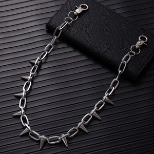 Detail of silver punk pant chain with sharp spikes and lobster clasps on leather background