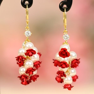 Detail view of cluster floral earrings with pearls and red roses on golden hooks
